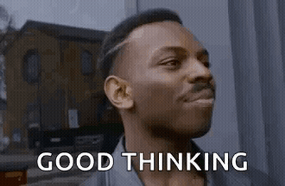 A Man Is Standing In Front Of A Building And Smiling . GIF