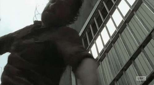 A Man Is Standing In Front Of A Building With A Ladder In His Hand . GIF
