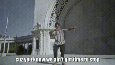 A Man Is Standing In Front Of A Building With The Words " Cuz You Know We Ain 'T Got Time To Stop " GIF