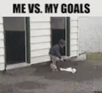 A Man Is Standing In Front Of A Building With The Words Me Vs. My Goals Above Him . GIF