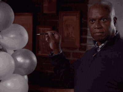 A Man Is Standing In Front Of A Bunch Of Balloons GIF