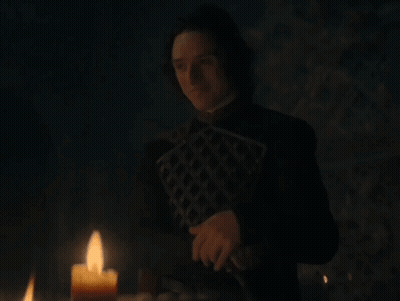 A Man Is Standing In Front Of A Candle In The Dark GIF