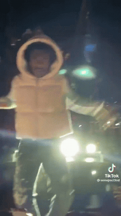 A Man Is Standing In Front Of A Car At Night . GIF
