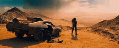 A Man Is Standing In Front Of A Car In The Desert . GIF
