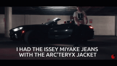 A Man Is Standing In Front Of A Car With The Words I Had The Issey Miyake Jeans With The Arc Teryx Jacket Below Him GIF