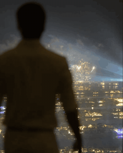 A Man Is Standing In Front Of A City Skyline At Night GIF