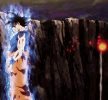 A Man Is Standing In Front Of A Cliff With A Red Light Behind Him . GIF
