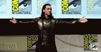A Man Is Standing In Front Of A Comic Con Banner GIF