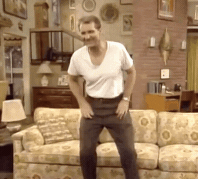 A Man Is Standing In Front Of A Couch In A Living Room . GIF