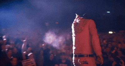 A Man Is Standing In Front Of A Crowd At A Concert Holding A Microphone GIF