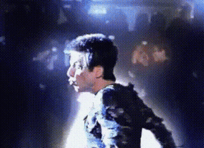 A Man Is Standing In Front Of A Crowd In A Dark Room With Blue Lights Behind Him . GIF