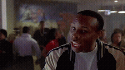 A Man Is Standing In Front Of A Crowd Of People In A Room . GIF