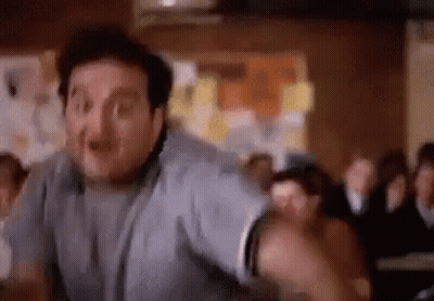 A Man Is Standing In Front Of A Crowd Of People In A Room . GIF