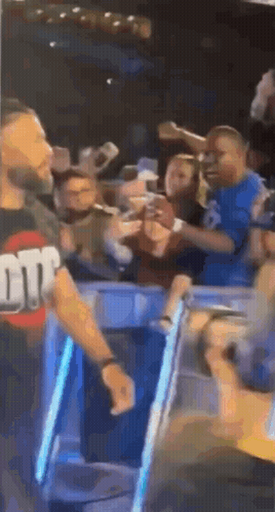 A Man Is Standing In Front Of A Crowd Of People In A Stadium . GIF