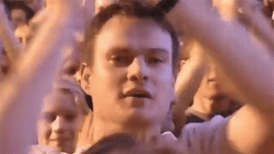 A Man Is Standing In Front Of A Crowd Of People With His Hands In The Air At A Concert . GIF