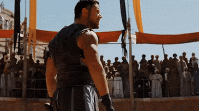 A Man Is Standing In Front Of A Crowd With A Sword GIF