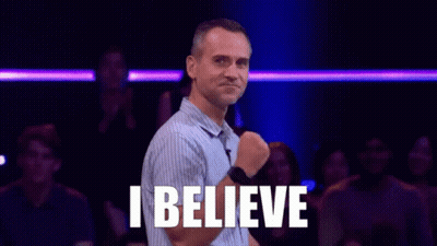 A Man Is Standing In Front Of A Crowd With The Words `` I Believe '' Written On His Chest . GIF