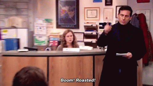 A Man Is Standing In Front Of A Desk Holding A Piece Of Paper And Saying Boom ! Roasted ! GIF