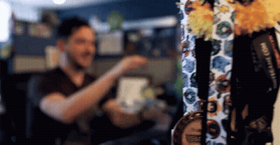 A Man Is Standing In Front Of A Display Of Medals And Lanyards . GIF