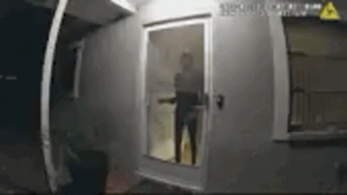 A Man Is Standing In Front Of A Door In A Room . GIF