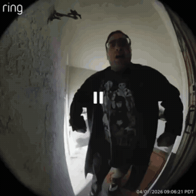 A Man Is Standing In Front Of A Door With A Ring Camera GIF