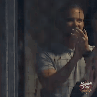 A Man Is Standing In Front Of A Double Fries Sign And Waving . GIF