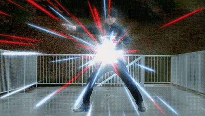 A Man Is Standing In Front Of A Fence With Red And Blue Lights Coming Out Of His Arms . GIF