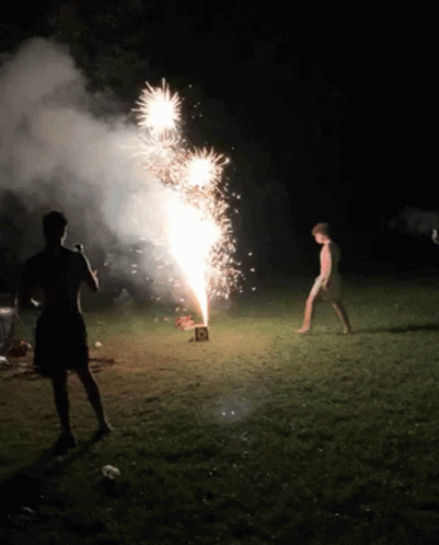 A Man Is Standing In Front Of A Firework Display With A Box That Says ' R ' On It GIF