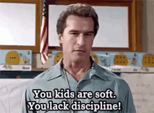 A Man Is Standing In Front Of A Flag In A Classroom And Talking To A Child . GIF