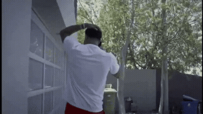 A Man Is Standing In Front Of A Garage Door Talking On A Cell Phone . GIF