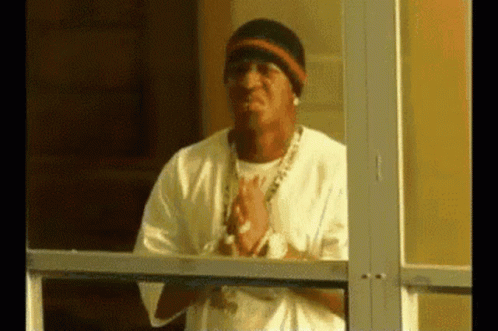 A Man Is Standing In Front Of A Glass Door With His Hands Folded . GIF