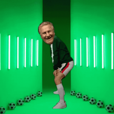 A Man Is Standing In Front Of A Green Wall With Soccer Balls GIF
