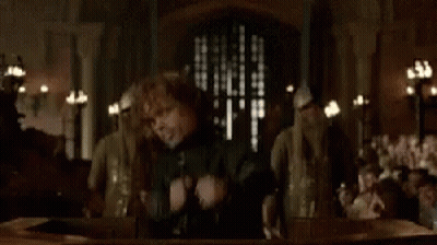 A Man Is Standing In Front Of A Group Of People Holding A Sword . GIF