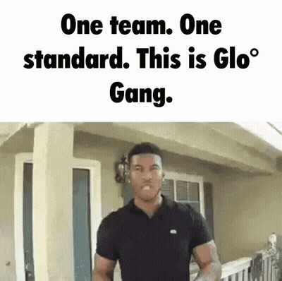 A Man Is Standing In Front Of A House With The Words One Team One Standard This Is Glo Gang GIF