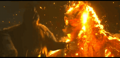 A Man Is Standing In Front Of A Large Fire GIF