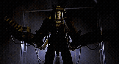 A Man Is Standing In Front Of A Machine That Looks Like A Robot With Wings . GIF