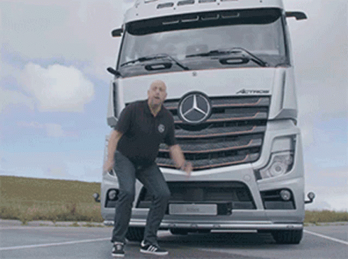 A Man Is Standing In Front Of A Mercedes Truck GIF