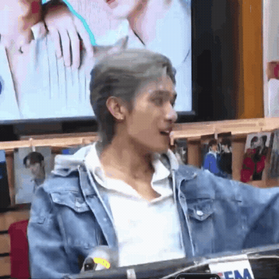 A Man Is Standing In Front Of A Microphone In A Room . GIF