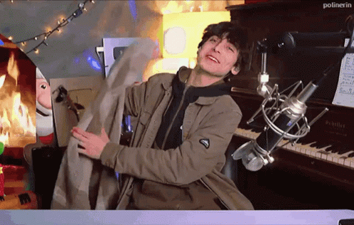A Man Is Standing In Front Of A Microphone With The Word Polinerin On The Bottom Right GIF