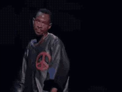 A Man Is Standing In Front Of A Microphone With The Words Next Time Written On The Screen Behind Him . GIF