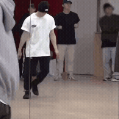 A Man Is Standing In Front Of A Mirror In A Dance Studio . GIF