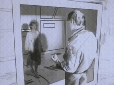 A Man Is Standing In Front Of A Mirror Looking At Himself In A Black And White Photo . GIF