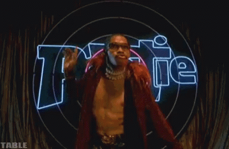 A Man Is Standing In Front Of A Neon Sign That Says " Table " GIF