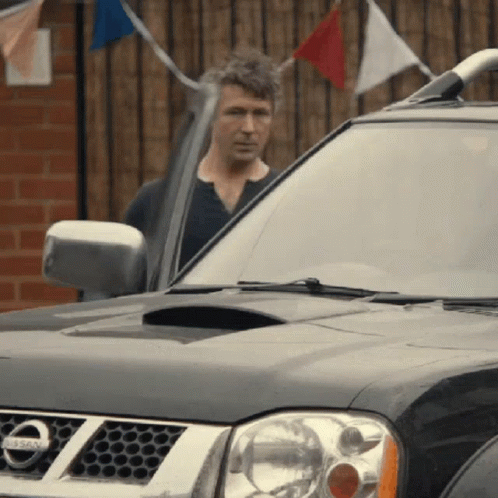 A Man Is Standing In Front Of A Nissan Car GIF