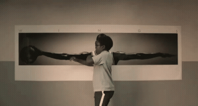 A Man Is Standing In Front Of A Picture Of A Person 'S Wings GIF