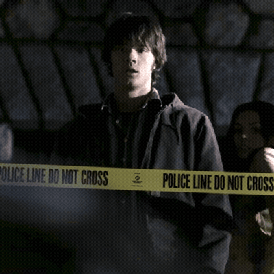 A Man Is Standing In Front Of A Police Line Do Not Cross Tape GIF