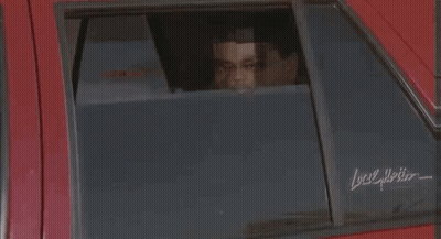 A Man Is Standing In Front Of A Red Car Holding A Plate . GIF