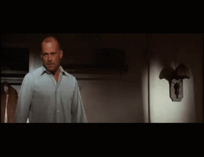 A Man Is Standing In Front Of A Refrigerator Door . GIF