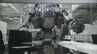 A Man Is Standing In Front Of A Robot That Has A Blue Light On The Front GIF