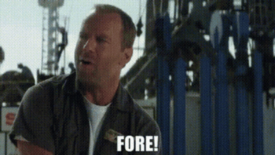 A Man Is Standing In Front Of A Roller Coaster Holding A Piece Of Paper And Saying Fore . GIF